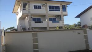 une maison avec une clôture blanche devant elle dans l'établissement apartamentos em ponta das canas, à Florianópolis