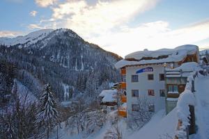 a building covered in snow with a mountain in the background at Alkira in Sankt Anton am Arlberg