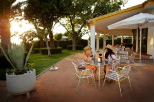 two women sitting at a table in a patio at Bungalows Bahia de la Plata in Zahara de los Atunes