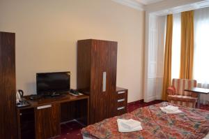 a hotel room with a bed, desk and television at Hotel Palacky in Karlovy Vary