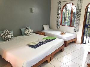2 camas en una habitación con 2 ventanas en La Perlita, en Jacó