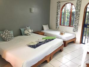 two beds in a room with two windows at La Perlita in Jacó