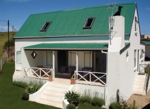 una pequeña casa blanca con techo verde en Aloe Cottage, en Darling