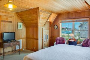 a bedroom with a bed and a tv and a window at The Castle Bed And Breakfast in Ocracoke
