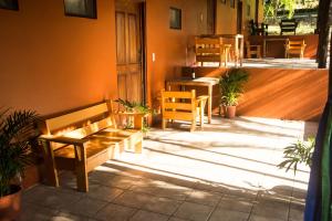 a patio with a bench and tables and chairs at Tsunami Hostel in Tamarindo