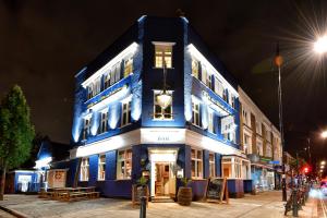 un edificio blu e bianco su una strada di notte di The Bridge Pub & Rooms a Londra