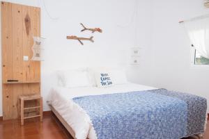um quarto branco com uma cama com um cobertor azul em Utopia em Aljezur