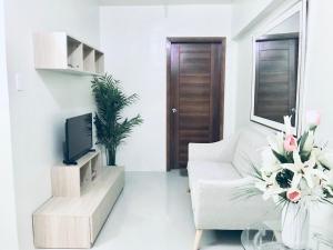 a living room with a white couch and a tv at Stunning Tropical resort condo in Mactan
