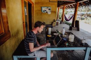 a man sitting at a table using a laptop computer at Bodhi Santa Catalina in Santa Catalina