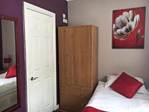 a bedroom with a bed and a cabinet with a red pillow at Glenmore Guesthouse in Southampton