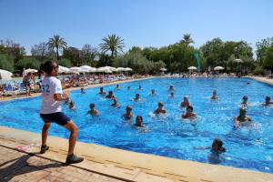 a boy standing in a swimming pool with a group of people at Valeria Madina Club - All Inclusive in Marrakech