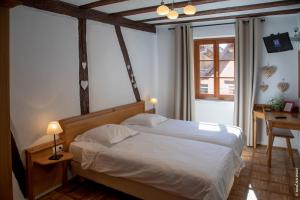 a bedroom with a bed and a lamp at Hôtel le Saint Nicolas in Riquewihr