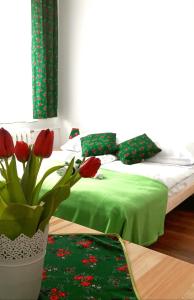 a bedroom with a bed with a green blanket and red tulips at Pokoje u Agi in Zakopane