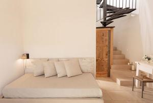 a bedroom with a bed with white pillows and a staircase at Masseria Mongiò dell'Elefante in Otranto