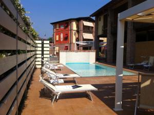 una fila de tumbonas y una piscina en un edificio en Luna Residence Hotel, en Casalmaggiore