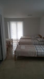 a bedroom with three beds and a window with blinds at Restoran ,, POGLED" in Han Pijesak
