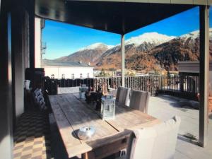 een houten tafel op een terras met uitzicht op de bergen bij chesa la posta in Samedan