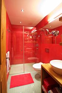 La salle de bains rouge est pourvue d'une douche et de toilettes. dans l'établissement chesa la posta, à Samedan