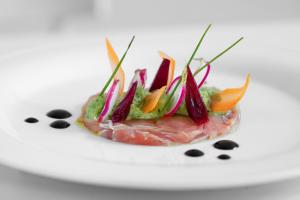 a piece of meat with vegetables on a white plate at Masseria Mongiò dell'Elefante in Otranto