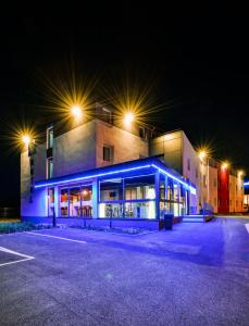 um edifício com iluminação azul num parque de estacionamento à noite em ibis Budget Mâcon Crêches em Chaintré