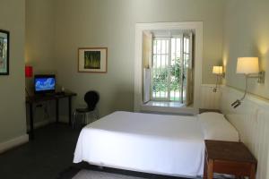 a bedroom with a white bed and a window at Hotel Plaza Malloa in Malloa