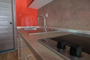 cocina con fregadero y pared roja en Avra Comfort Rooms - Family, en Nea Potidaea