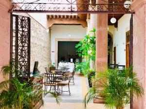 Hotel Expres By Hosting House في موريليا: فناء في الهواء الطلق مع طاولات وكراسي ونباتات