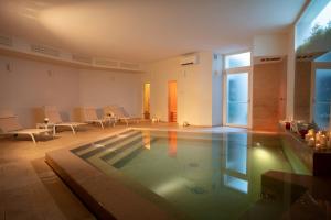 a swimming pool in a room with chairs and a table at Masseria Mongiò dell'Elefante in Otranto