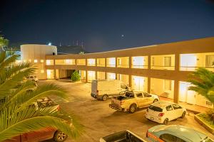 un gran edificio con coches estacionados en un estacionamiento en American Inn Hotel & Suites Parral en Hidalgo del Parral