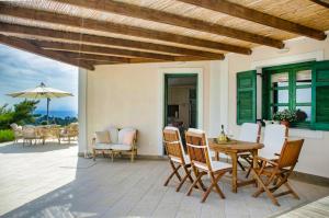 a patio with a table and chairs and an umbrella at SEAVIEW DAISY HOUSE IN ZAKYNTHOS ISLAND in Vasilikos