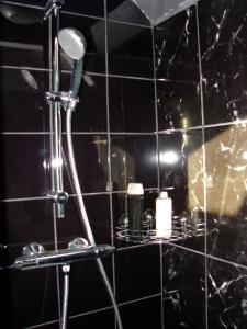 a black tiled bathroom with a shower with a mirror at yinloft in Sainte-Gemme-Moronval