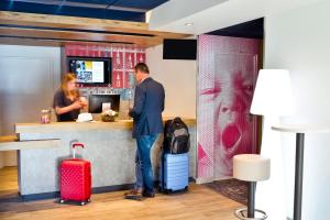 a man standing at a counter with luggage at ibis Budget Mâcon Crêches in Chaintré