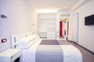 a white bedroom with a bed and a tv at Excelsior in Piombino