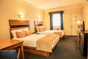 a hotel room with two beds and a television at American Inn Hotel & Suites Parral in Hidalgo del Parral