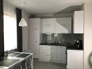 a kitchen with white cabinets and a table with chairs at Apartament koloru morza - Szmaragd in Łeba