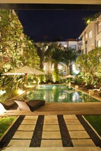 a pool with chairs and an umbrella in a building at Umalas Apartment in Seminyak