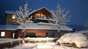 ein schneebedecktes Haus mit Bäumen davor in der Unterkunft Haus Bellevue in Obertraun
