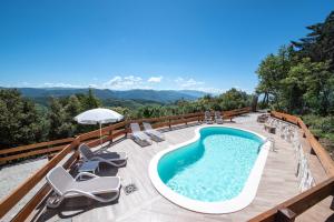 una piscina en una terraza con sillas y sombrilla en VillaSubasioRelax, en Spello