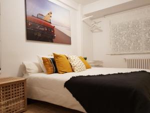 a bedroom with a bed with yellow pillows and a painting on the wall at APART XXlll 24h CATEDRAL Garaje in Santiago de Compostela