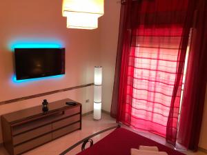 a living room with a tv and red curtains at Casa Vacanza nel cuore di Castellammare del golfo in Castellammare del Golfo