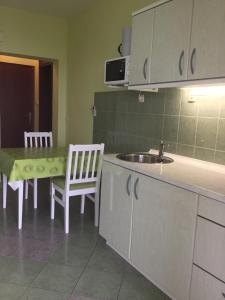 uma cozinha com um lavatório, uma mesa e cadeiras em Apartments Žgogo em Trogir