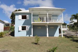 a blue house with a balcony on a yard at La villa larimar in Saint-François