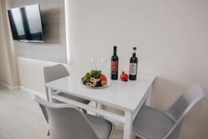 a white dining room table with wine bottles and a plate of fruit at Swiss Quality Apartments (Beach Tower) in Batumi