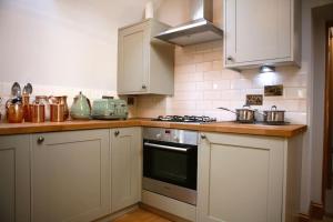 a kitchen with white cabinets and a stove top oven at Providence Cottage a Sussex boutique retreat for two in Angmering