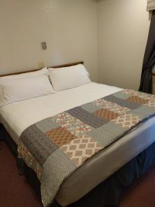 a bed with a quilt on it in a room at The BarnwooD Inn in Humansville