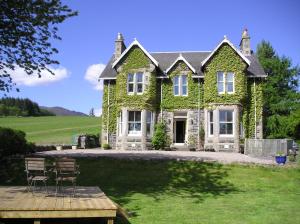 a house covered in ivy with chairs in the yard at Kinnaird Country House in Pitlochry