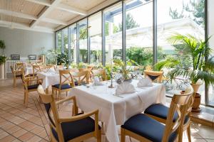 a restaurant with white tables and chairs and windows at Hotel Am Sommerbad in Halberstadt
