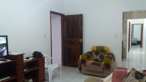 een woonkamer met een stoel en een televisie bij Casa Praia Arpoador in Peruíbe