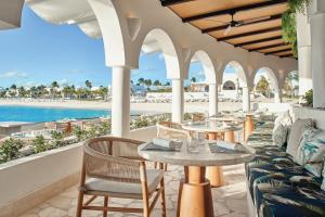 an outdoor patio with tables and chairs and the beach at Cap Juluca, A Belmond Hotel, Anguilla in West End Village