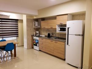 Una cocina con un refrigerador blanco y una mesa. en Malvinas Departamentos, en San Rafael